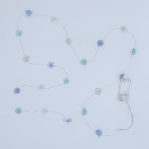 May include: A string of decorative LED lights featuring seashell and starfish shapes in shades of blue, green, and white. The lights are battery-operated and suitable for indoor use. The string measures approximately 6 feet in length.