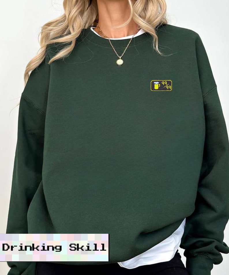 May include: A dark green sweatshirt with a small yellow and black graphic on the chest. The graphic appears to be a stylized beer mug. The text "Drinking Skill" is at the bottom of the image.