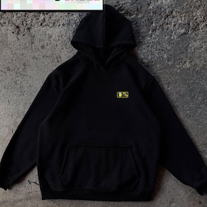 May include: Black hoodie with a front pocket and hood. The text "DRINKING SKILL" is displayed in a white rectangle at the top. A small yellow and black graphic is on the left chest.
