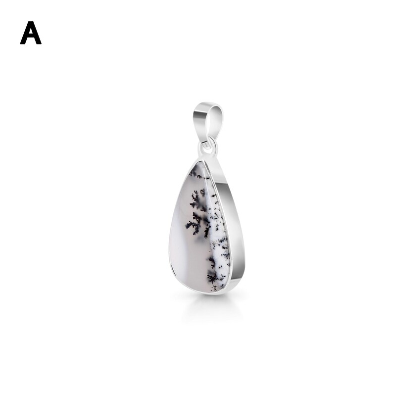 May include: A teardrop-shaped pendant featuring a white stone with black dendritic fern-like inclusions, set in a polished silver-toned metal frame with a matching bail at the top. The letter A is visible in the upper left corner of the image.