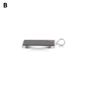 May include: A rectangular pendant featuring a dark brown stone with lighter brown inclusions, set in a polished silver-toned metal frame. The pendant includes a silver-toned metal bail attached to one side for hanging on a chain or cord.