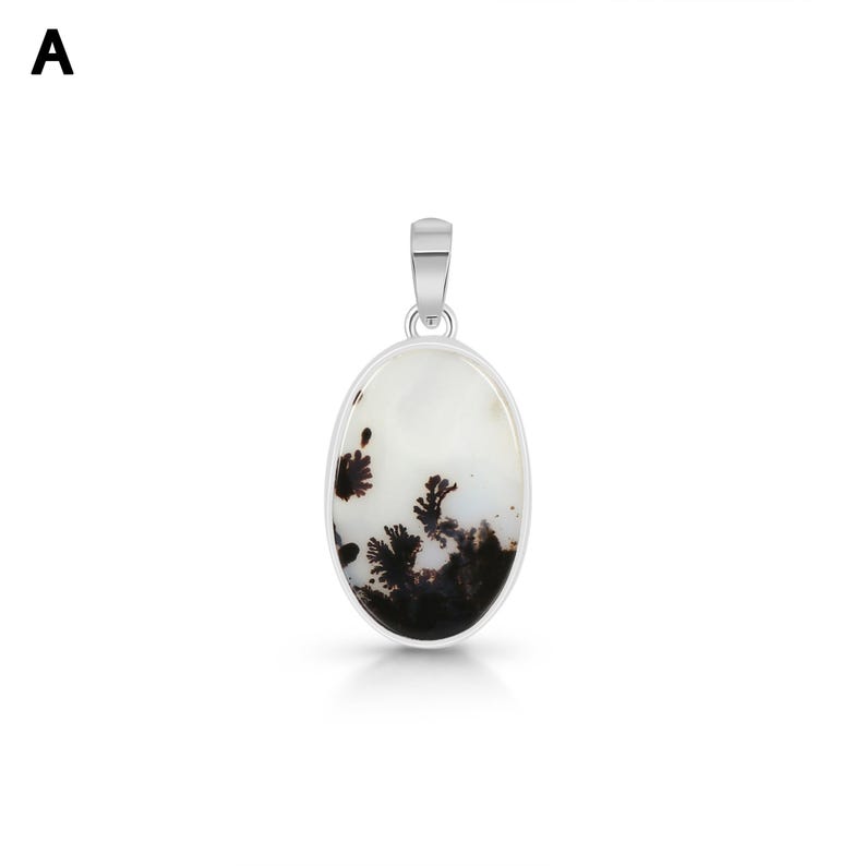 Puede incluir: Un colgante de forma ovalada que presenta una piedra blanca con inclusiones dendr&iacute;ticas oscuras en forma de &aacute;rbol. La piedra est&aacute; engastada en un marco de metal plateado liso y pulido con una anilla plateada a juego en la parte superior.