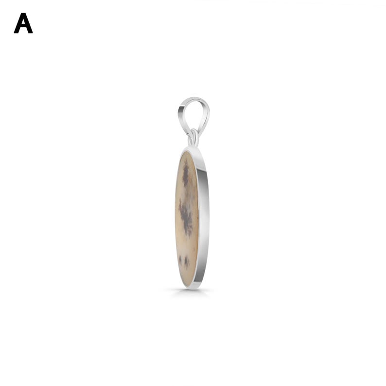 May include: A silver pendant featuring an oval-shaped stone with a cream-colored base and dark brown dendritic inclusions. The pendant has a polished silver metal frame and a small silver bail at the top for attachment to a necklace chain.