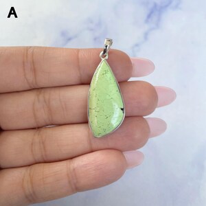 Pu&ograve; includere: Un ciondolo a forma di goccia con una pietra liscia verde lime chiaro con venature scure, incastonato in una montatura in metallo color argento lucido con un piccolo gancio integrato sulla parte superiore per una catenina o un cordino.