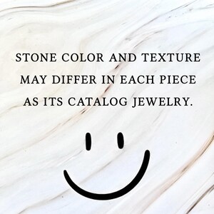 以下が含まれることがあります： 大理石模様の背景に「STONE COLOR AND TEXTURE MAY DIFFER IN EACH PIECE AS ITS CATALOG JEWELRY」の文字。 画像の下部には黒いスマイリーフェイスがあります。