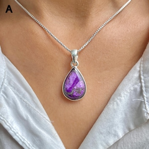 May include: A teardrop-shaped purple and grey stone pendant set in a silver-toned metal bezel. The pendant hangs from a thin, silver-toned box chain necklace. The stone features a marbled texture with deep violet and muted grey color variations.