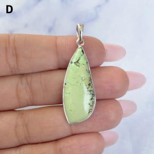 Pu&ograve; includere: Un ciondolo a forma di goccia con una pietra liscia verde lime chiaro caratterizzata da motivi a matrice scuri e ramificati. La pietra &egrave; incastonata in una montatura in metallo color argento lucido con un piccolo gancio argentato in cima.