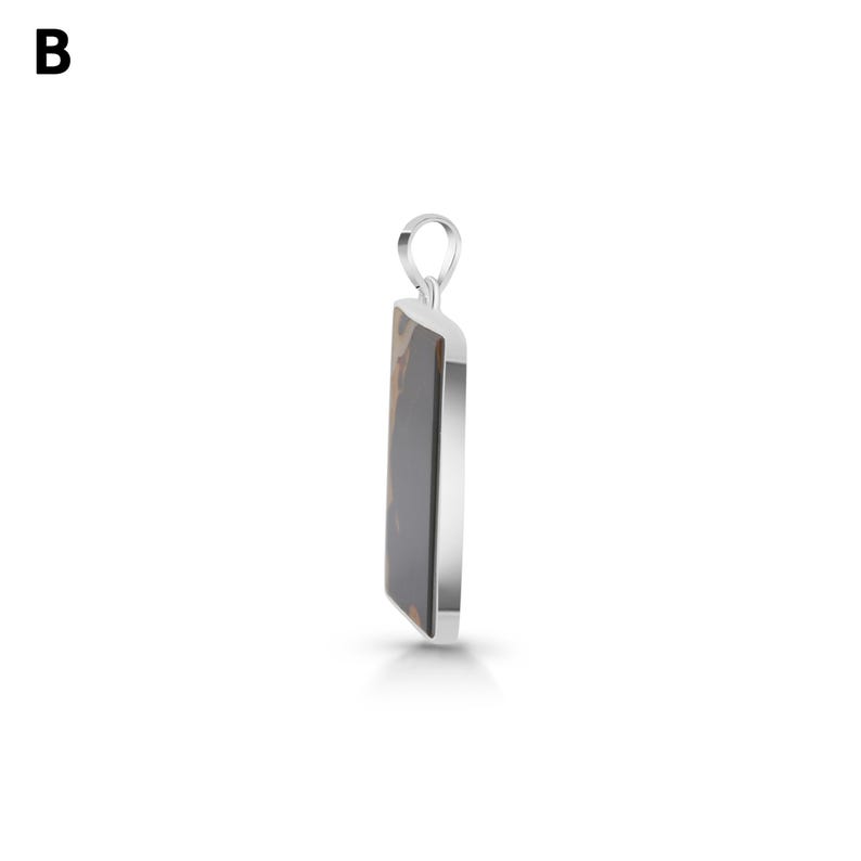 May include: A rectangular pendant featuring a smooth, dark brown and black patterned stone inlay set within a polished silver-toned metal frame. The pendant includes a small, circular silver-toned bail at the top for attachment to a chain.