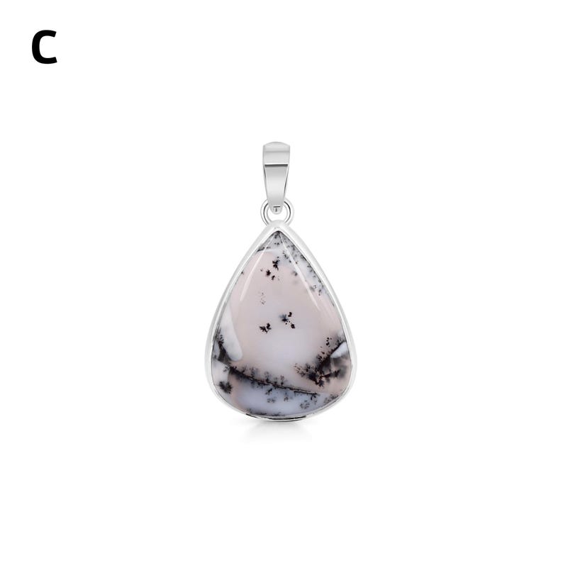 May include: A teardrop-shaped pendant featuring a smooth, pale pinkish-white stone with dark, branching dendritic inclusions. The stone is set in a polished silver-toned metal bezel with a matching silver-toned bail at the top for suspension.