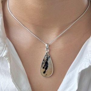 May include: A silver chain necklace with a teardrop-shaped pendant featuring a natural agate stone with brown and white patterns.