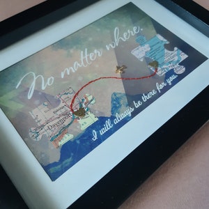 May include: A framed piece of art with a map background and red string connecting two gold heart charms. The text "No matter where. I will always be there for you." is written in white on a blue background.