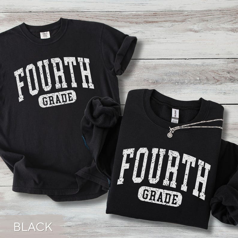 May include: A black short-sleeved t-shirt and a black long-sleeved sweatshirt, both featuring the white distressed text "FOURTH GRADE" printed in a collegiate font. The garments are displayed together, showcasing the matching graphic design.