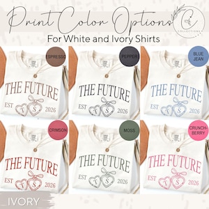 May include: Ivory-colored t-shirts with the text "THE FUTURE" and heart-shaped graphics, available in various print colors like Espresso, Pepper, Blue Jean, Crimson, Moss, and Crunch-Berry. The shirts are displayed with a necklace.