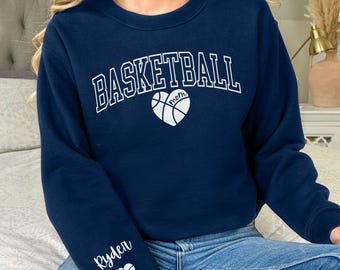 May include: Navy blue sweatshirt with the text "Basketball Mom" in white with a basketball heart graphic. The left sleeve has the name "Ryden" in white with a basketball heart graphic.
