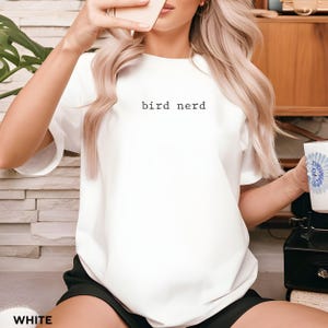May include: White t-shirt with the text "bird nerd" printed on the front.