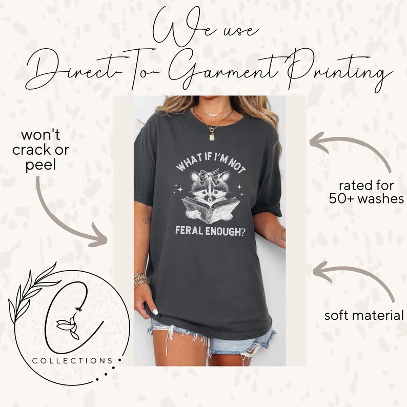 May include: A dark gray t-shirt with a white graphic of a raccoon reading a book. The text on the shirt reads "What if I'm not feral enough?"