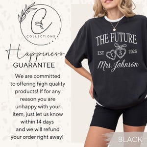 May include: Black t-shirt with the text "THE FUTURE EST 2026 Mrs. Johnson" in white. The shirt features two heart-shaped designs with the letters "T" and "S". The image also includes a logo and text that reads "Happiness GUARANTEE".