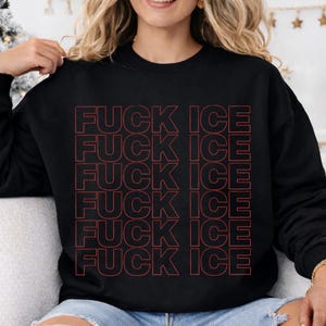 Pode incluir: Camisola preta com a frase "FUCK ICE" em vermelho, empilhada verticalmente. O texto &eacute; em negrito, sem serifa. A camisola &eacute; de estilo casual.