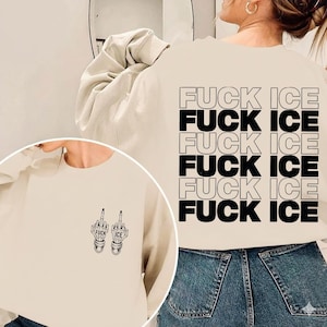 Pode incluir: Camisola bege com o texto "FUCK ICE" repetido em letras pretas nas costas. A frente apresenta um gr&aacute;fico de duas m&atilde;os de esqueleto a fazer o dedo do meio, com as palavras "FUCK ICE" em cada m&atilde;o.