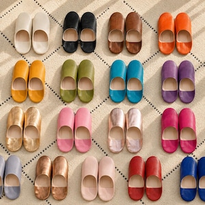 Puede incluir: Una colección de dieciséis pares de zapatillas sin cordones dispuestas en una cuadrícula, con una variedad de colores sólidos que incluyen blanco, negro, marrón, naranja, amarillo, verde oliva, turquesa, morado, dorado, rosa, oro rosa, magenta, gris, bronce, beige, rojo y azul.