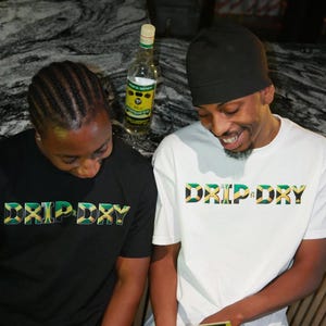 May include: Two people wearing black and white t-shirts with the text "DRIP DRY" in green, yellow, and black. The text is stylized to look like the Jamaican flag.