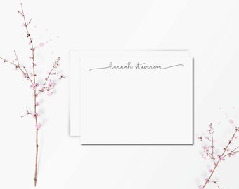 May include: A stack of two rectangular white stationery cards featuring the name hannah stevenson printed in a thin black cursive script at the top center, accompanied by two thin brown branches with small light pink flower blossoms.