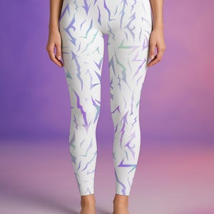 May include: White leggings featuring a repeating pattern of jagged, lightning bolt-like shapes in purple and teal. The leggings are high-waisted and form-fitting, suitable for athletic activities or casual wear.