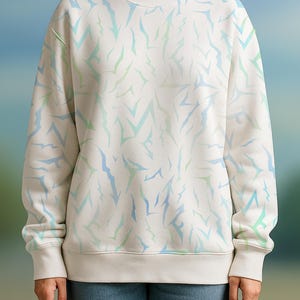 May include: Cream-coloured sweatshirt featuring a repeating pattern of blue and green abstract shapes. The long-sleeved top has a crew neck and ribbed cuffs and hem. The model is wearing blue jeans.