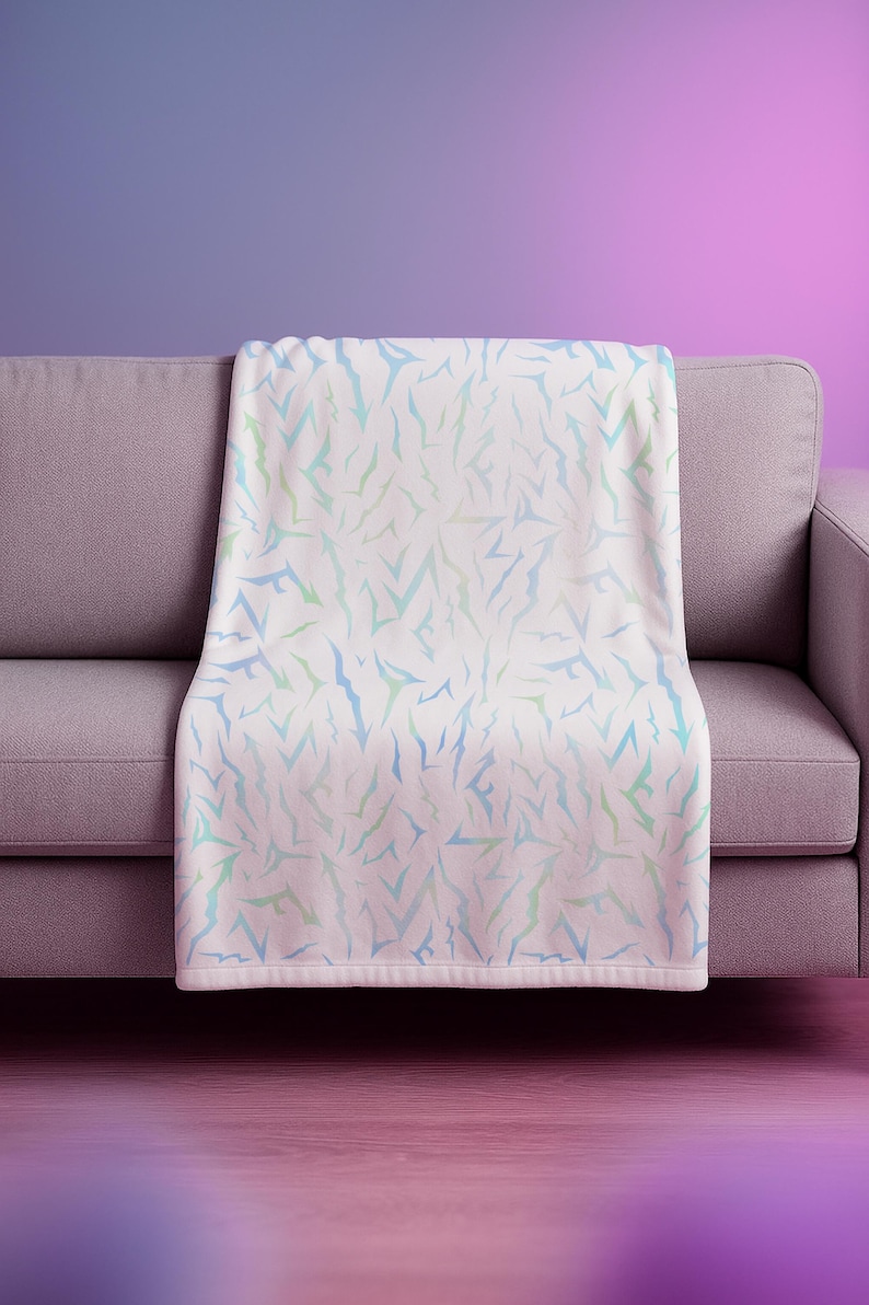May include: A white throw blanket with a pattern of blue and green abstract shapes, draped over a grey sofa. The background gradient transitions from purple to pink.