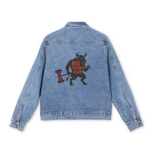 Könnte beinhalten: Hellblaue Jeansjacke mit Knopfverschluss. Auf der Rückseite befindet sich eine Grafik eines Stiers, der eine Axt hält, mit den roten Worten "BIG FEELINGS CLUB" und "CHANGE".