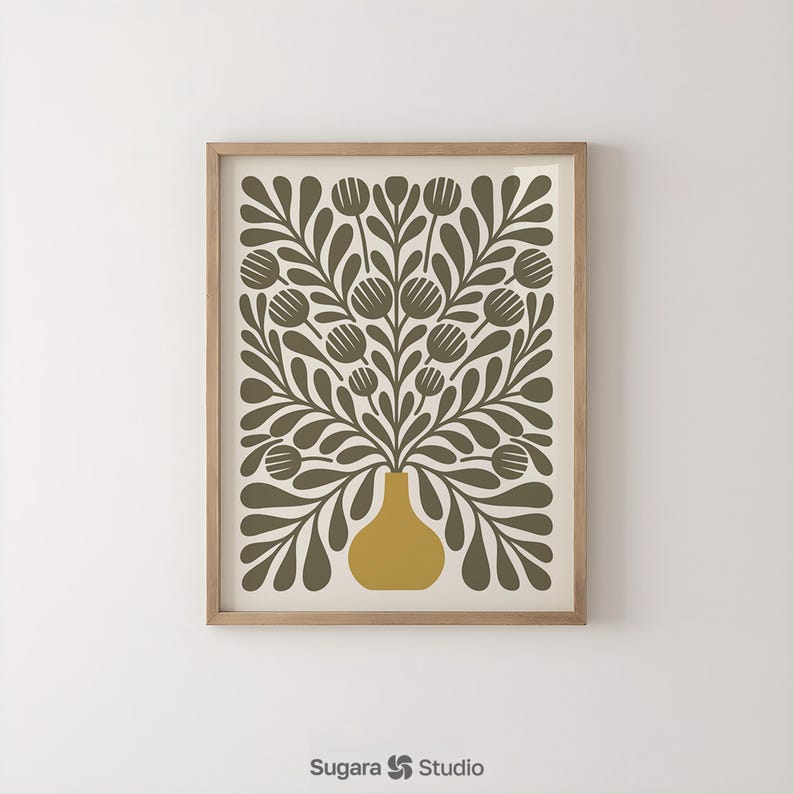 May include: A framed art print featuring a stylized floral design. The artwork showcases a mustard-yellow vase holding olive-green leaves and flower-like shapes against a cream background. The print is enclosed in a light-brown wooden frame.