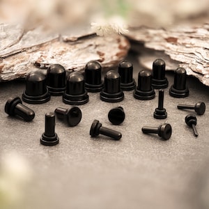 May include: A set of black ear gauges in various sizes and styles. The gauges are made of surgical steel and have a smooth, polished finish.