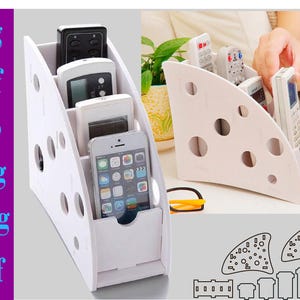 Può includere: Organizzatore per telecomandi in plastica bianca con quattro slot. L'organizzatore ha un design a forma di formaggio svizzero ed è posto su un tavolo.
