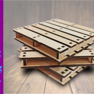 May include: A stack of four wooden pallets, each with a rectangular shape and black edges. The pallets are made of light brown wood and are stacked on top of each other.
