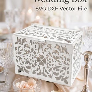 May include: A white rectangular wedding box featuring intricate laser-cut floral patterns on all sides and a slotted lid. The text "Create Your Wedding Box SVG DXF Vector File" is printed above the box in a dark gray serif font.