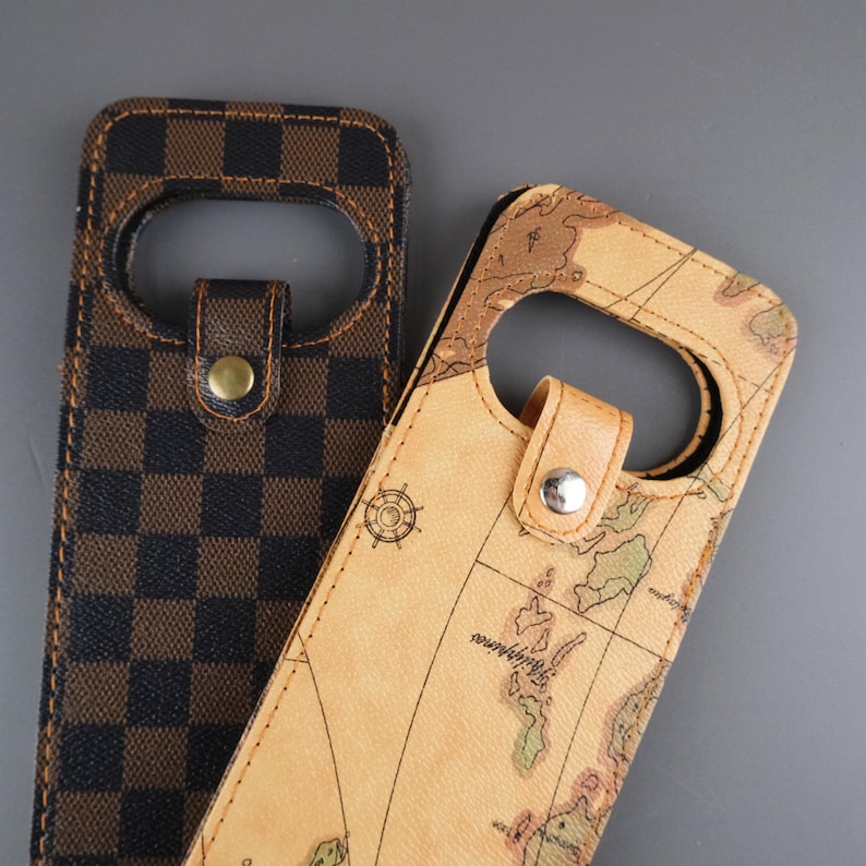 K&ouml;nnte beinhalten: Zwei Handyh&uuml;llen. Eine ist in braunem und schwarzem Karomuster, die andere ist beige mit einem Weltkarten-Design.
