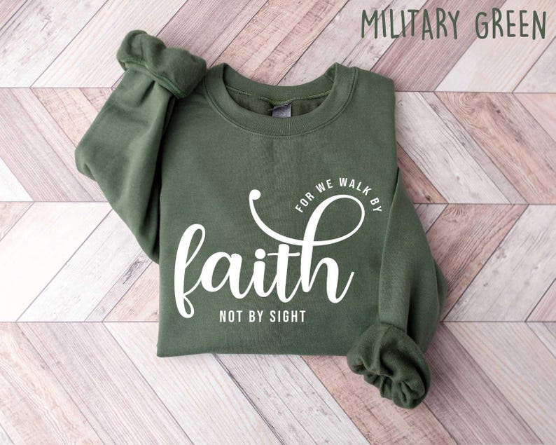 Puede incluir: Una sudadera verde con el texto "For we walk by faith not by sight" en letras blancas.