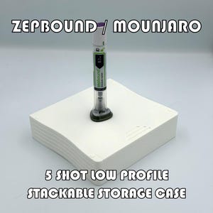 May include: A white, stackable storage case with the text "ZEPBOUND / MOUNJARO" and "5 SHOT LOW PROFILE STACKABLE STORAGE CASE." A disposable injection pen is inserted into the case. The pen is white, green, and clear.