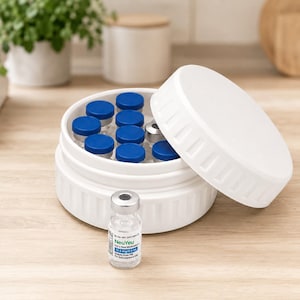 May include: A white, round container with a lid, holding multiple small vials with blue caps. A single vial with a silver cap and a label that reads "NeuYeu" is in front of the container. The container is on a light wood surface.