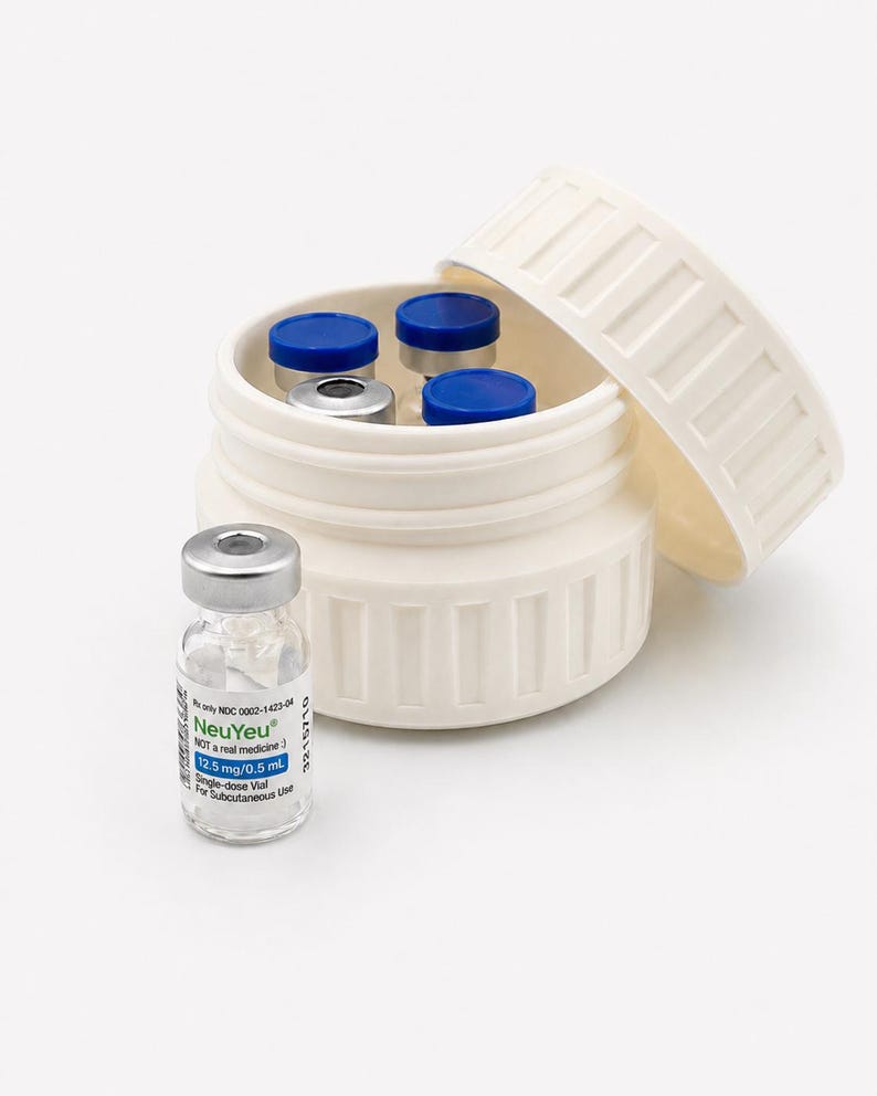 May include: A white, cylindrical container with a partially open lid, holding several small vials with blue and silver caps. A single vial with the text "NeuYeu" is in front of the container. The vials are for subcutaneous use.
