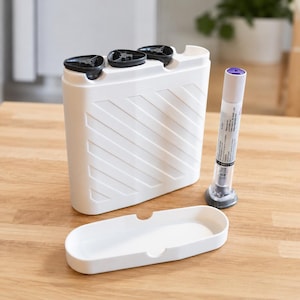 May include: A white plastic container with three black lids, a matching tray, and a clear medical device with a purple cap. The container has a diagonal textured pattern. The items are on a wooden surface.