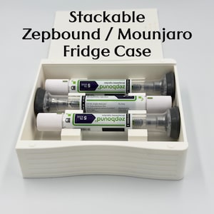 May include: A white, stackable fridge case with the text "Stackable Zepbound / Mounjaro Fridge Case" in black. Inside, three single-dose pens are visible. Each pen is white with green and black labeling.