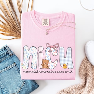 May include: Pink t-shirt with the word "NICU" in a patchwork design, featuring floral, gingham, and baby footprint patterns. A teddy bear, duck, and baby bottle are also shown. The text "neonatal intensive care unit" is printed below.