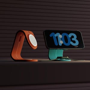 May include: Two phone stands, one orange and one teal, with a phone on the teal stand displaying the time 11:03. The stands are made of a flexible, ribbed material.