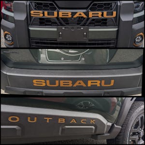 May include: A composite image showing exterior details of a dark green vehicle. The top section displays a black grille with the word SUBARU in copper lettering. The middle section shows a black bumper with SUBARU in copper. The bottom shows OUTBACK in copper.