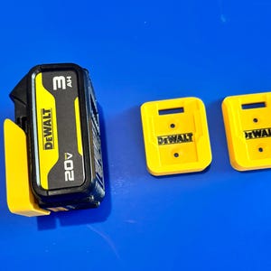 May include: A black and yellow DeWalt 20V 3Ah battery with two yellow battery holders. The battery has the DeWalt logo and is on a blue surface.