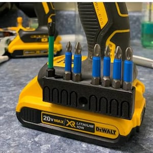 May include: A close-up of a yellow and black DeWalt cordless drill with a black bit holder containing several silver and blue drill bits. The drill is labeled "20V MAX XR LITHIUM ION".
