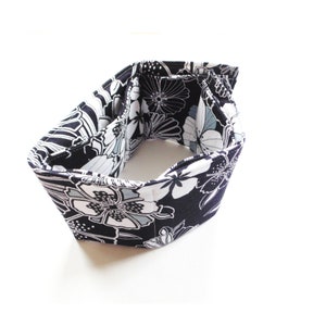 May include: A black and white floral fabric wallet with multiple compartments. The wallet is folded and closed, showing the exterior fabric design.