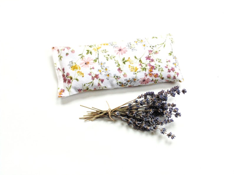 Organic lavender eye pillow made of soft flannel and has pretty flowers on a white background. Filled with flaxseed, rice, and lavender. Can be heated in microwave or kept in freezer. Use for cold or warm therapy.