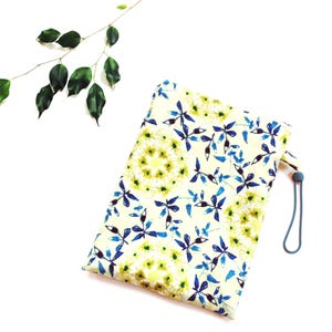 May include: A rectangular pouch with a floral pattern in blue, green, and yellow on a cream background. The pouch has a teal drawstring and a small loop. A sprig of green leaves is in the upper left corner.